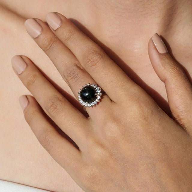A refined 925 sterling silver cocktail ring featuring a single natural Black Star gemstone in a classic round cut (11 mm,...