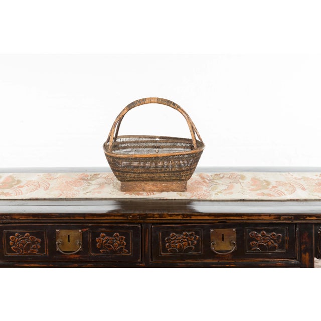 A Chinese rustic vintage woven rattan market basket from the mid 20th century, with large handle and rectangular base....