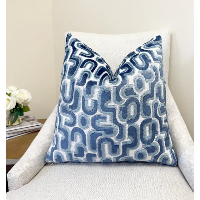 This pillow showcases a layered blue velvet design on a textured white bouclé background, combining depth with softness....