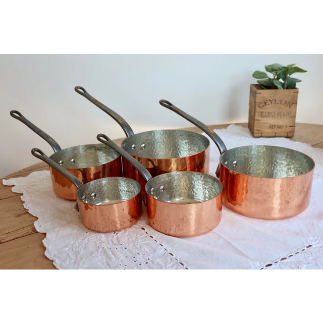 Set of 5 hammered copper saucepans, characterized by handcrafted work where the metal is shaped by hammer blows, creating...