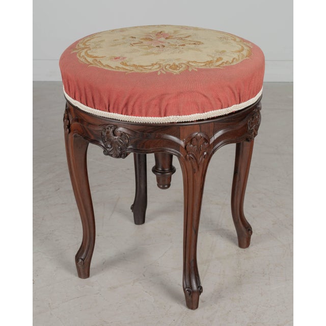A 19th century French Louis XV style adjustable swivel stool made of solid rosewood with hand-carved details, sturdy...