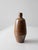 A vintage handmade studio pottery vase with a tall, tapered form and narrow bottleneck opening. Finished in a warm brown...
