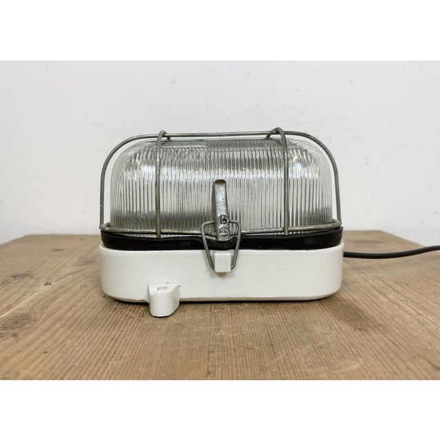 Vintage industrial light made in Poland during the 1970s. It features a white porcelain body and a ribbed glass cover. The...