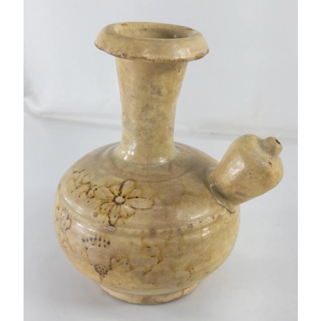 We are selling this very interesting and unique Kendi vessel with floral design in the glaze. We are unsure of the origin...