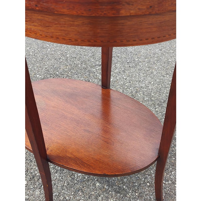 This is a stunning mid-century Mersman tiered oval side table, crafted from rich mahogany. It features elegant inlays, and...