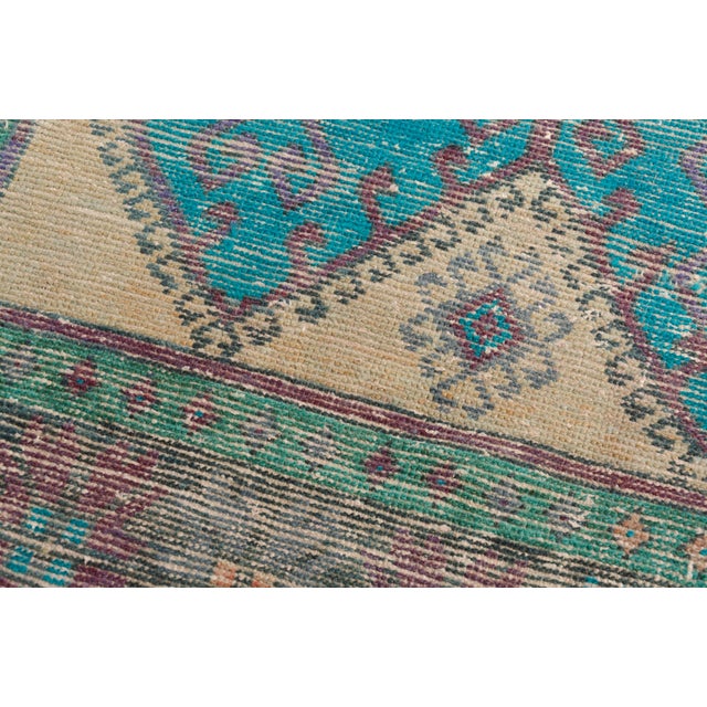 This is a vintage Turkish Oushak rug from the Mid 20th Century. The piece was hand-knotted.
