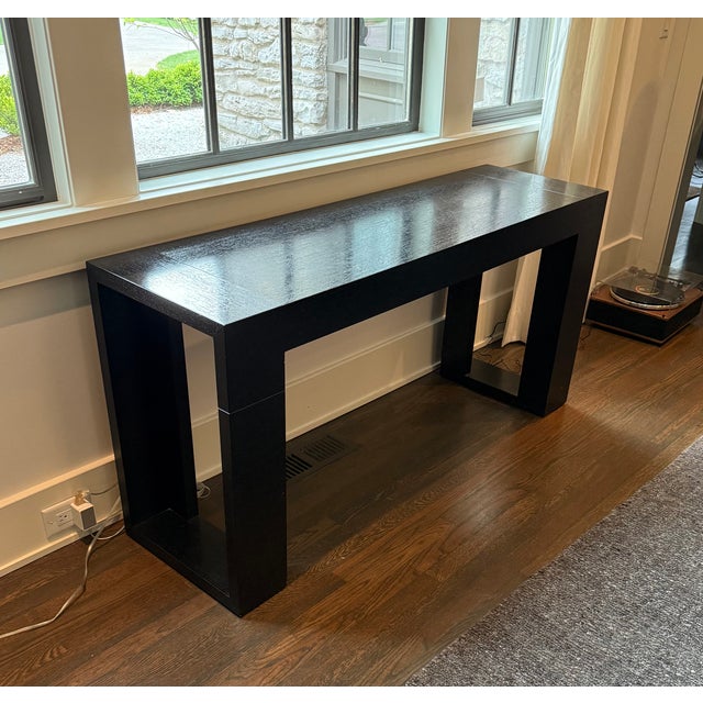 A striking, dark wood console table with inset details on the legs. 60”W x 18”D x 29.25”H