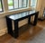 A striking, dark wood console table with inset details on the legs. 60”W x 18”D x 29.25”H