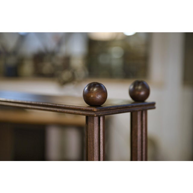 An elegant five-tiered shelf in stained beech, supported by four turned uprights and finished with ball feet, a chic echo...