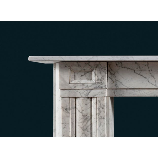 An antique Regency Carrara Marble fireplace surround with square corner blocks, the cushion moulded jambs with quarter-...