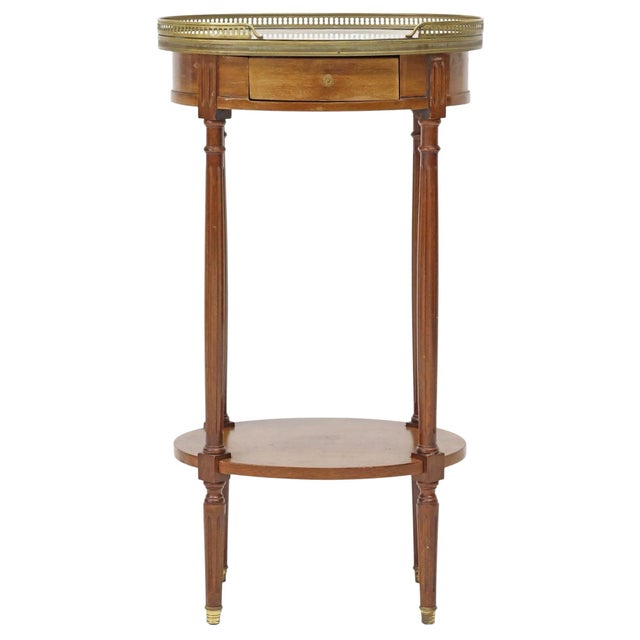 An elegant French Louis XVI style mahogany side table featuring a beautifully figured white marble top framed by a pierced...
