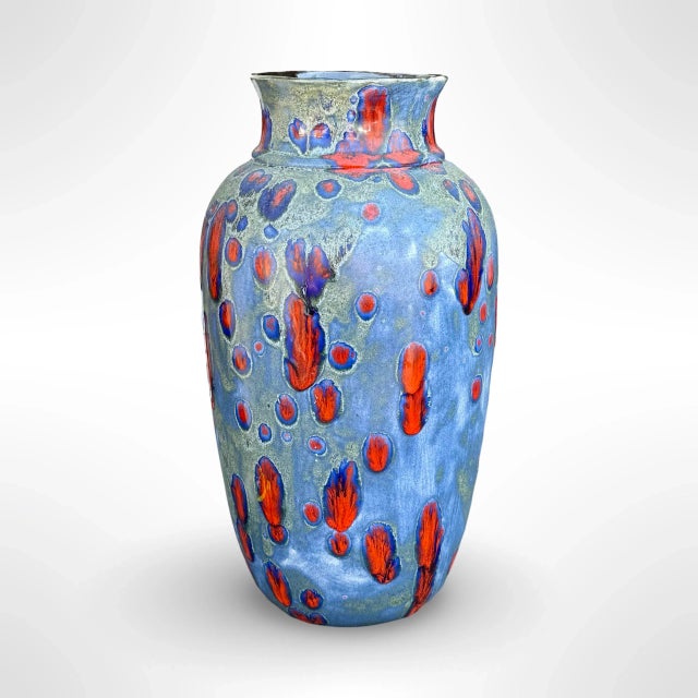 A striking studio art pottery vase featuring a rich, flowing drip glaze in vivid tones of blue, red, green, and hints of...