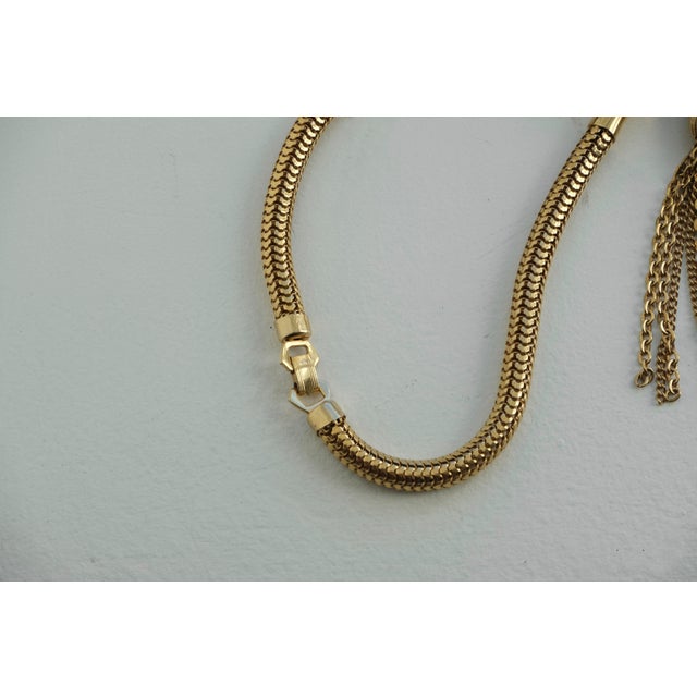 Vintage gold-tone snake chain tassel choker necklace from the 1970s. The choker features a thick serpentine chain with a...