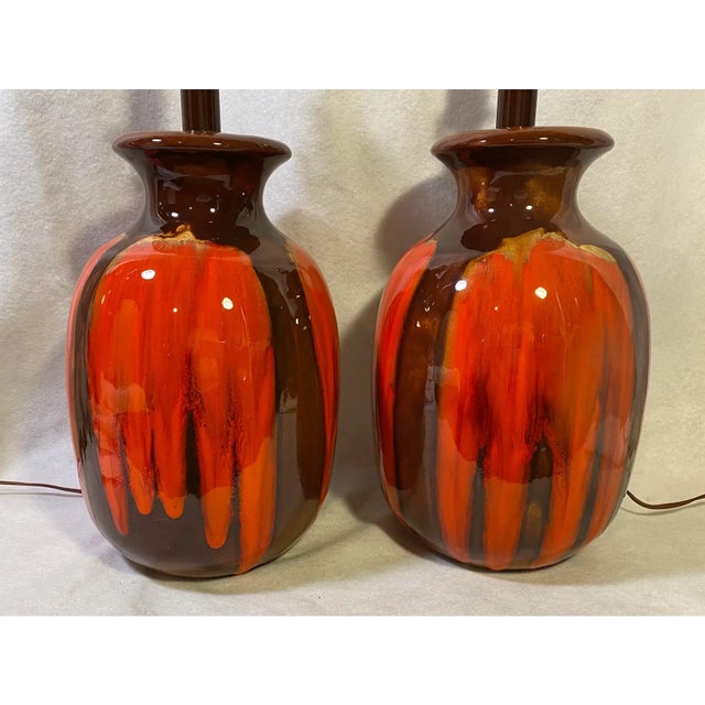 pair of stunning Mid Century ceramic table lamps with a vibrant orange and brown glossy drip glaze finish. Both of these...