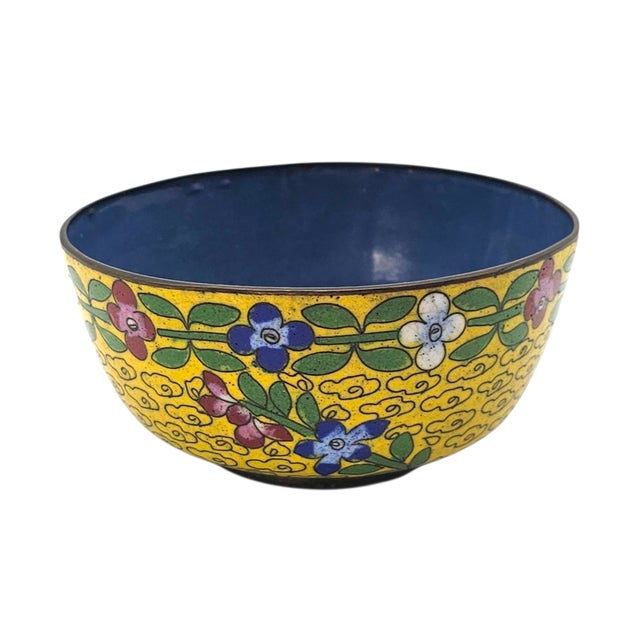 In the curve of this small vessel, color lingers like memory—yellow ground alive with blossoms in blue, red, and white,...