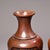 Beautiful matched pair of handcrafted solid copper vases. Each vessel features raised high-relief chased panels with a...