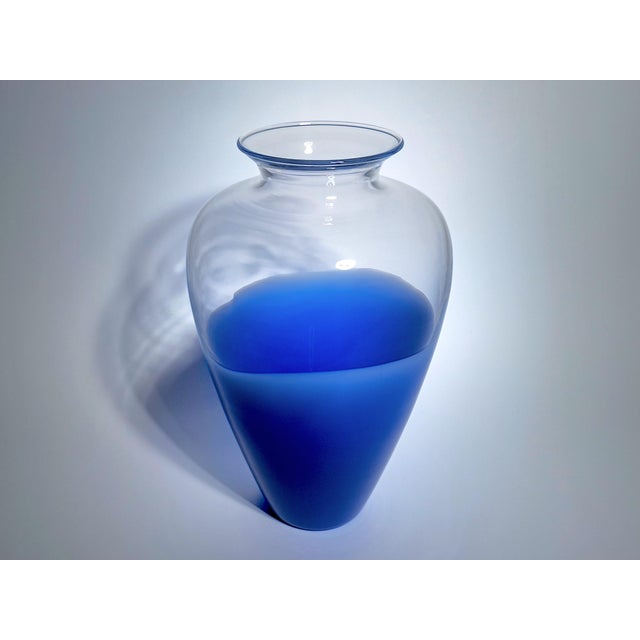 Vintage vase from the 1980s, made by Effetre Murano, in clear glass with a distinctive blue base. The contrast between the...
