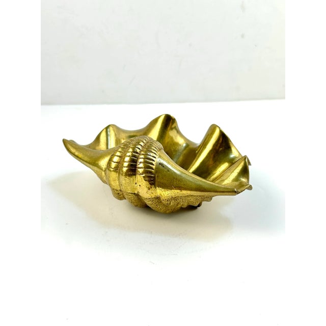 A sculptural vintage brass clamshell dish with dramatic curves and rich golden patina. Seashell forms became popular...