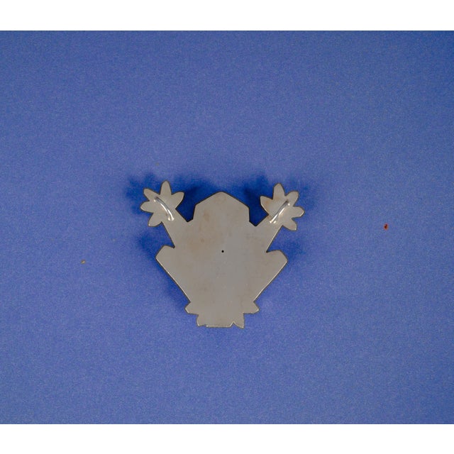 Handmade unique silver graphic frog. On the back are two eyelets. The frog is made by a goldsmith and is hollow on the...