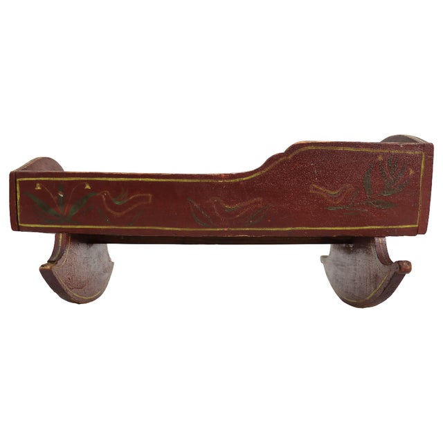 Antique folk art wooden doll cradle, attributed to circa 1860, with a red-painted finish and hand-stenciled decoration....