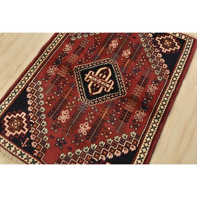 An authentic vintage tribal Shiraz rug hand-knotted with fine wool and natural dyes. This nomadic rug features a central...