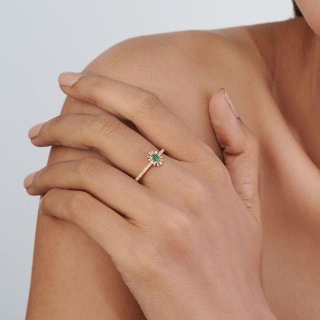 This elegant sunburst ring features a vibrant 0.08 ct emerald and diamond, set in 14k yellow gold. The center stone...