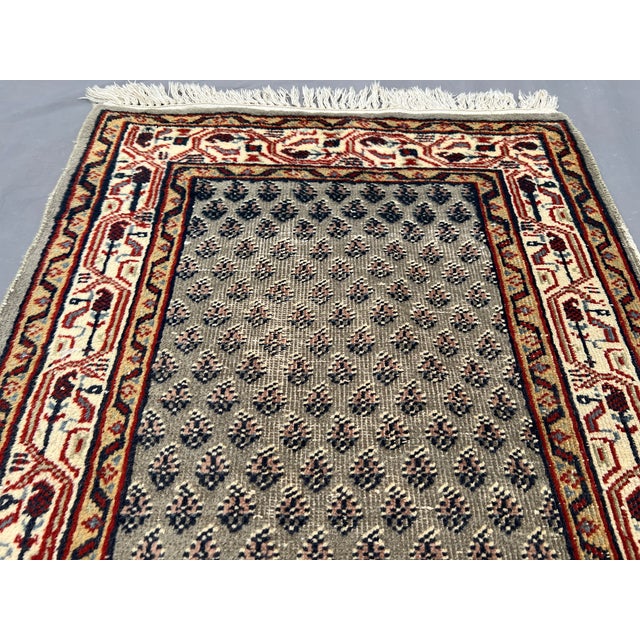 This vintage Moroccan hand-knotted rug features a classic tribal pattern with a rich palette of earthy gray, red, and...