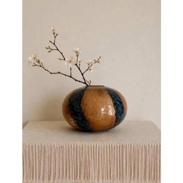 A striking oversized Sasaki Glass art glass vase featuring a dramatic low-profile orb silhouette with rich amber tones...