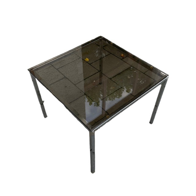 A coffee table with a simple, modernist form based on geometric shapes. The structure is made of chrome-plated profiles,...