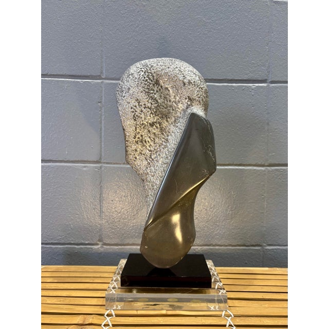 A striking vintage postmodern abstract sculpture, hand carved from stone and mounted on a dramatic stacked black and clear...