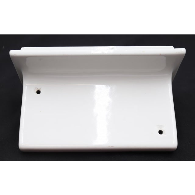 Flush mount rectangular bathroom shelf made of white porcelain over ceramic. There are two predrilled holes for drainage....