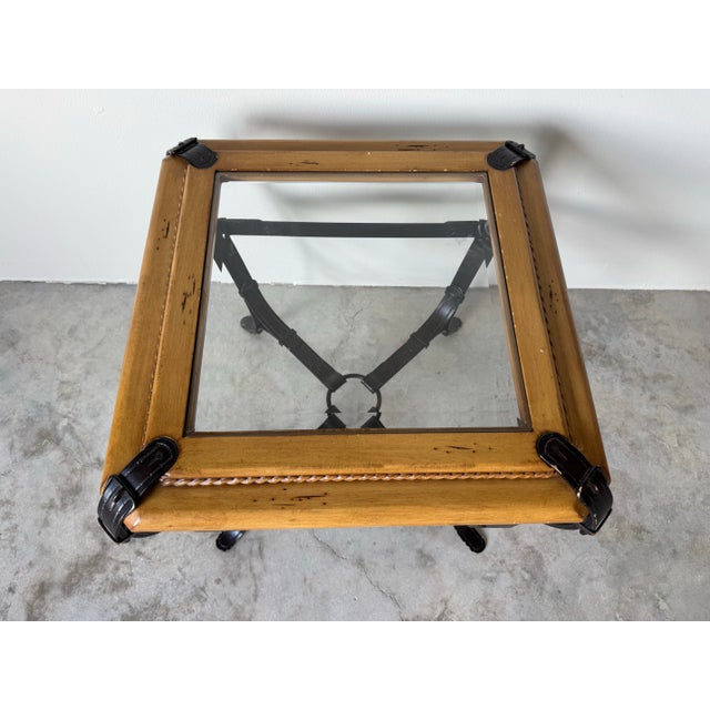 Elegant vintage end table in the Adnet Hermès style, featuring a forged metal base with strap and buckle details, a carved...