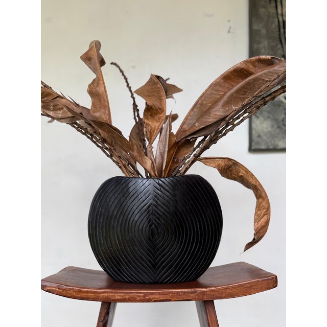 A vessel that blurs the line between functional form and contemporary sculpture. Hand-carved from solid mango wood, this...