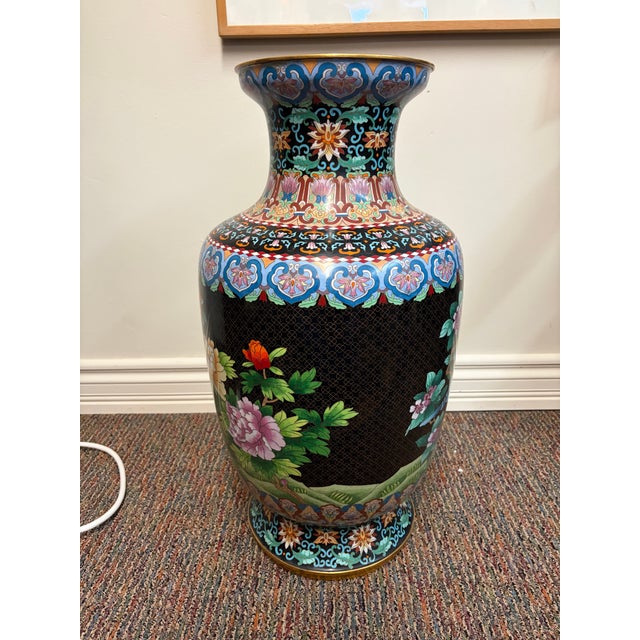 This is a large Chinese cloisonné enamel vase. It is decorated with vibrant flowers and birdlife on a rich black...