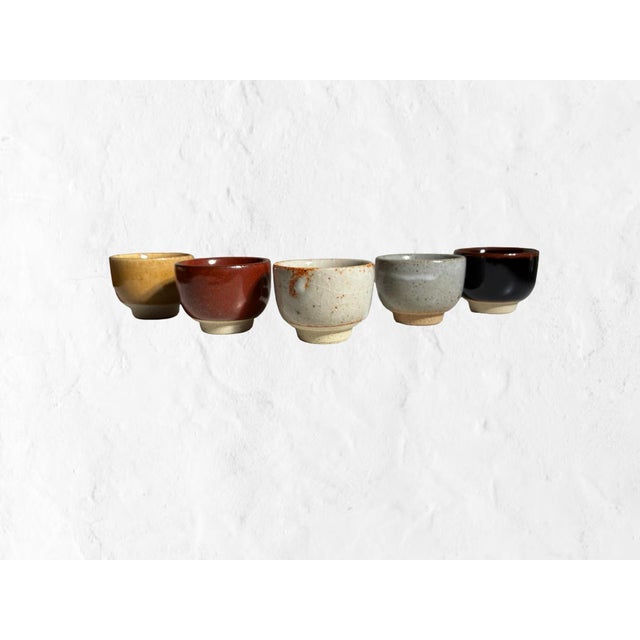 A beautifully cohesive set of five Japanese studio pottery yunomi and sake cups finished in warm, earthy glazes ranging...