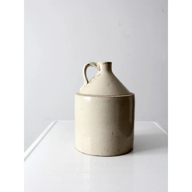 This is an antique stoneware crock jug. This antique utilitarian piece is a beautiful statement in the kitchen displayed...