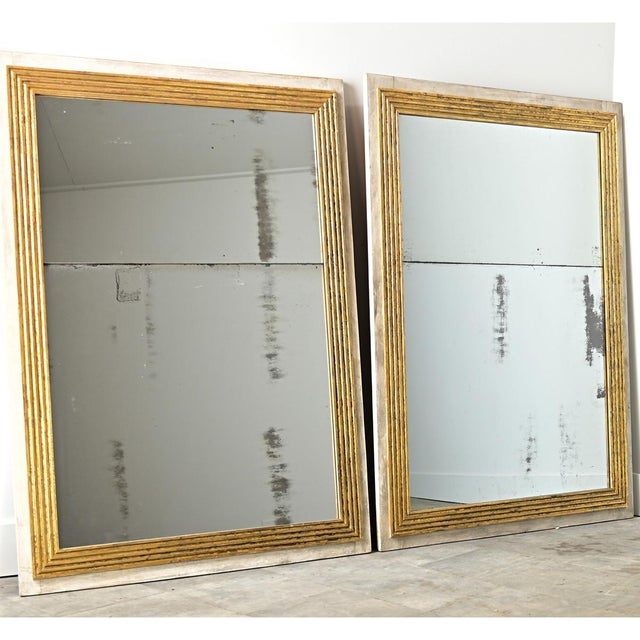 An exciting pair of French mirrors framed in classic reeded molding of the Louis XVI taste that reflects the luster of...