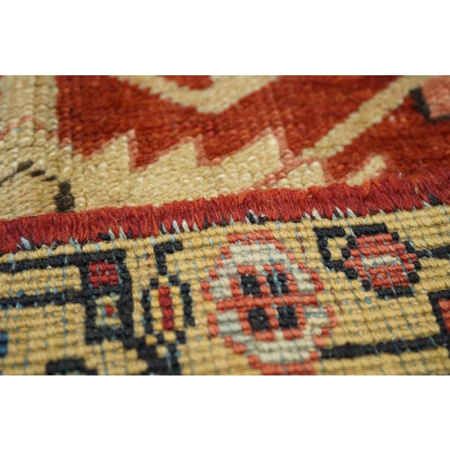 A small central medallion extends long arms ending in huge ragged, dark blue pendants, on the madder red field decorated...