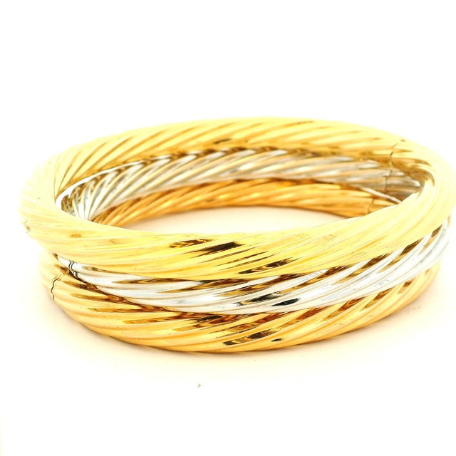 A beautifully substantial trio of Italian hinged bangle bracelets, crafted in 18-karat yellow and white gold and dating to...