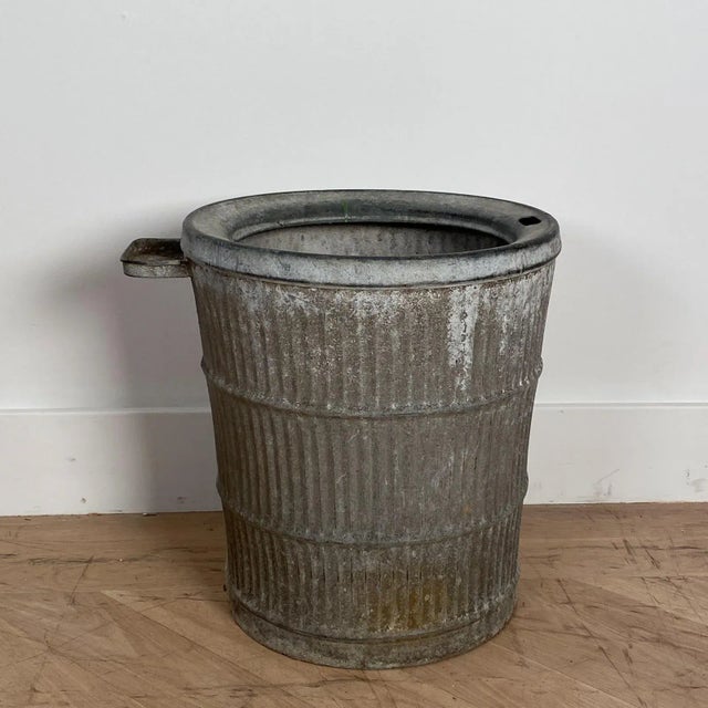 A large antique zinc bucket with ribbed decoration.