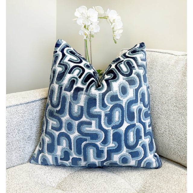 This pillow showcases a layered blue velvet design on a textured white bouclé background, combining depth with softness....