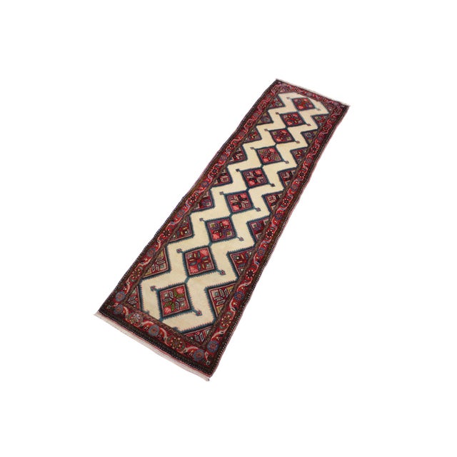 beautiful hand-knotted wool runner rug measuring approximately 2.6 x 9.9 feet. The rug features a striking ivory field...