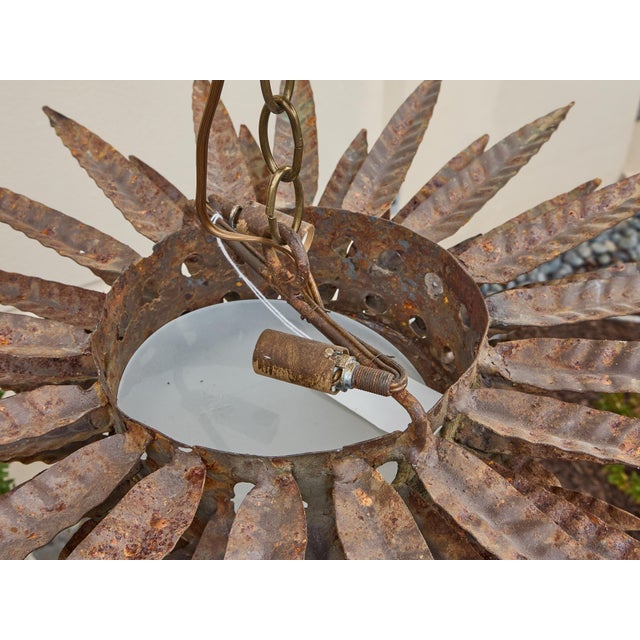 A dramatic Spanish Midcentury sunburst light fixture, crafted in gilt hammered metal with striking sculptural presence....