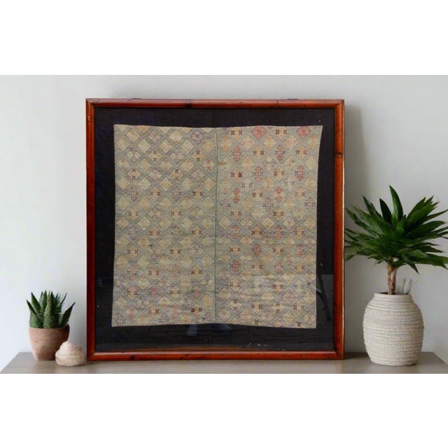 This beautiful antique textile, likely an antique baby carrier from the Hmong people of Southeast Asia, whispers tales of...