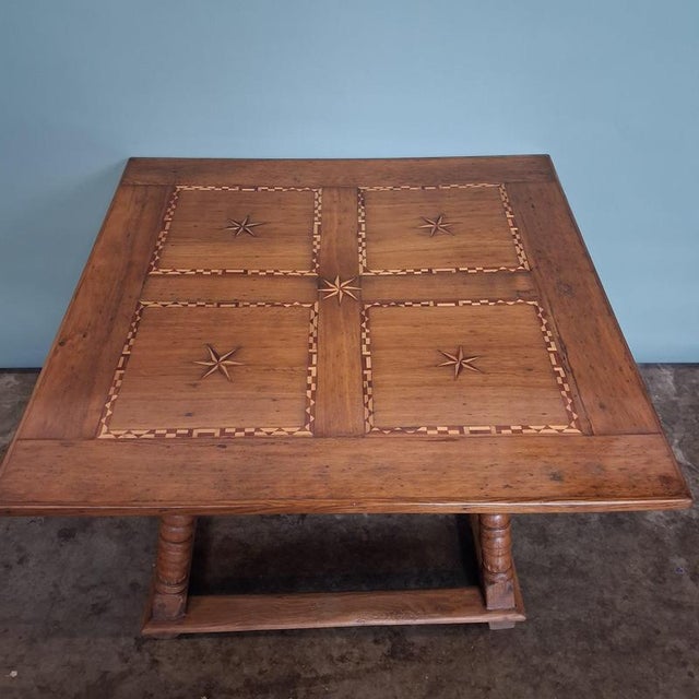 This antique table captivates with its expressive inlaid tabletop featuring star motifs and its robust construction in...