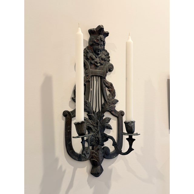 Striking pair of antique French Victorian wall sconces featuring finely cast figural faces, scrolling arms, and classical...