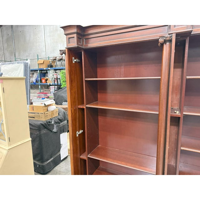Elegant vintage cherry wood bookcase featuring a beautifully crafted classical design with decorative columns, carved...