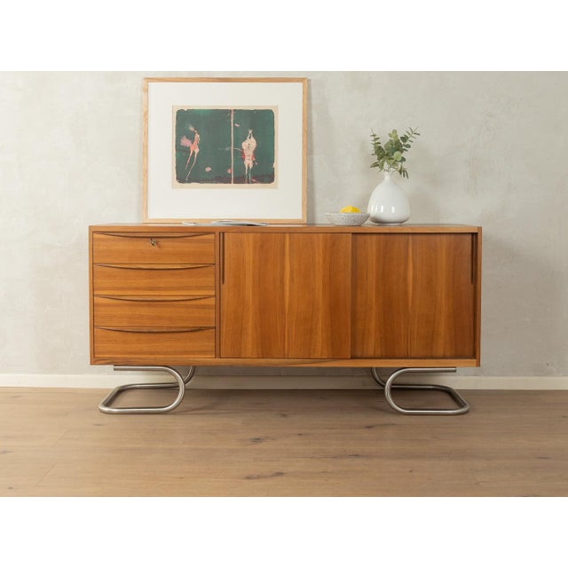 A stunning, partially solid wood sideboard in Scandinavian style from the 1950s. The body is finished in walnut veneer and...