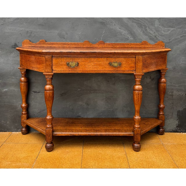 Spanish console table dating to the early 20th century. The piece features a shaped top with a small raised back, a...