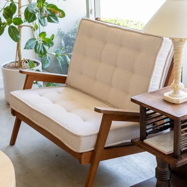 Beautiful oak wood settee from France, 1950's. Original light wood frame with angled arms and legs. Newly upholstered seat...